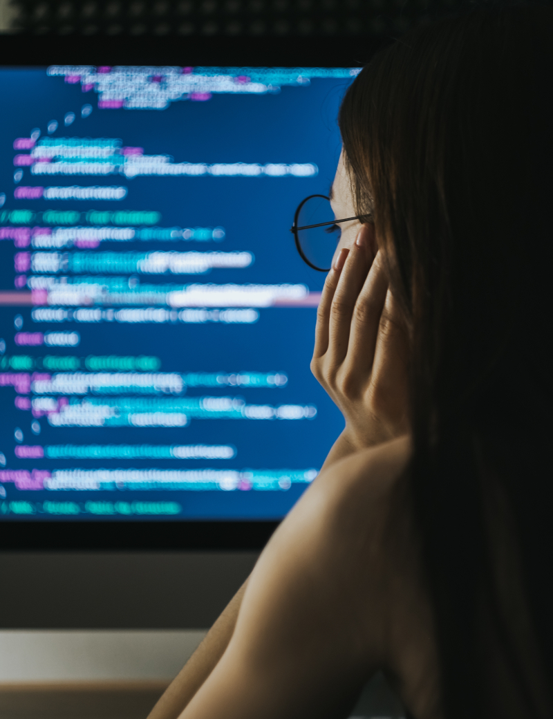Female software engineer looking at code on computer screen