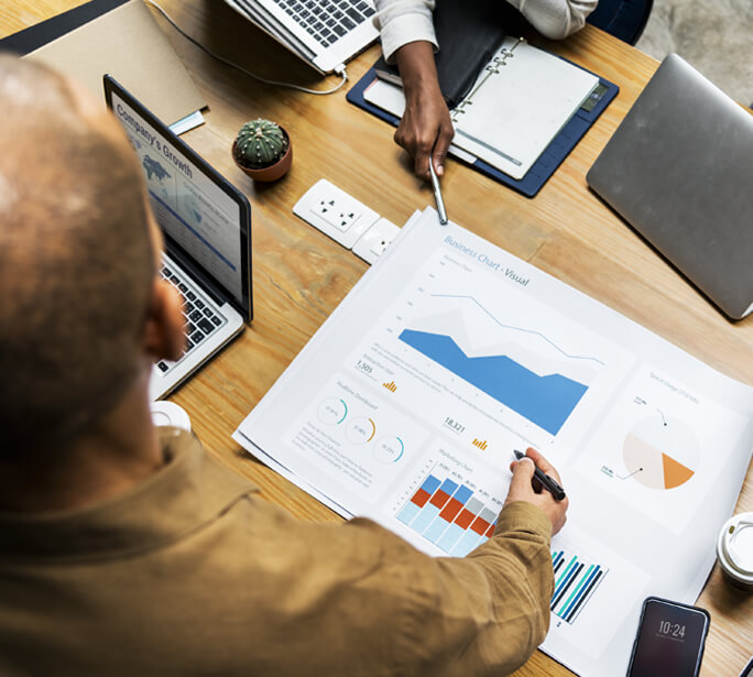 Business owner and colleague looking at reports and charts on paper